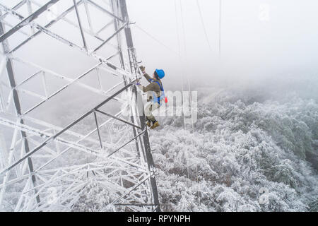 (190223) -- Wuhan, 23 février 2019 (Xinhua) -- photos prises le 12 février 2019, Wang Chaolin électricien montre l'ascension de la tour de transmission de puissance pour les réparations de pointe dans la région de montagne de Wuhan, capitale de la province du Hubei en Chine centrale. Une équipe d'électriciens a été envoyé pour réparer un fil haute tension qui a été rompu en raison de l'épaisse couche de l'accumulation de glace. Après une journée de travail sur le plus de 40 mètres de haut de la tour de transmission de puissance de mauvaise condition météorologique, l'équipe réussi à fixer la défaillance de l'alimentation système qui réduit la vitesse des trains causant des retards au cours de l'après-pic des voyages vacances. Cette année Banque D'Images