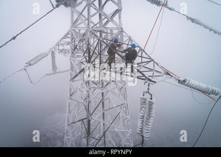 (190223) -- Wuhan, 23 février 2019 (Xinhua) -- photo aérienne prise le 12 février 2019 montre d'urgence Dong Jinbing (L) de l'inspection du fil haute tension avec son collègue Wang Wensheng sur la tour de transmission de puissance dans la zone de montagne de Wuhan, capitale de la province du Hubei en Chine centrale. Une équipe d'électriciens a été envoyé pour réparer un fil haute tension qui a été rompu en raison de l'épaisse couche de l'accumulation de glace. Après une journée de travail sur le plus de 40 mètres de haut de la tour de transmission de puissance de mauvaise condition météorologique, l'équipe réussi à fixer la défaillance de l'alimentation système qui réduit la vitesse des trains ca Banque D'Images