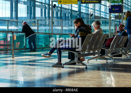 Femme assise au voyageur à la recherche d'attente téléphonique, l'aéroport d'Alicante, Alicante, Valence, Espagne, Europe Provence Banque D'Images