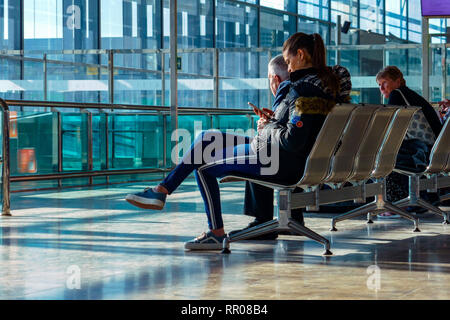 Femme assise au voyageur à la recherche d'attente téléphonique, l'aéroport d'Alicante, Alicante, Valence, Espagne, Europe Provence Banque D'Images