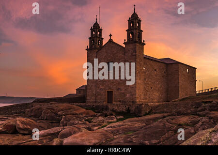 L'église de Virgen de la Barca, Muxia, Galice, Espagne tourné au coucher du soleil, beaucoup d'orange et de pourpre dans le ciel à partir d'un angle faible Banque D'Images