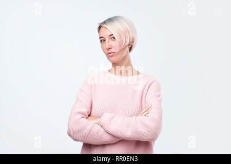 Sûr de graves hipster girl in pink sweater posant avec les mains croisées Banque D'Images