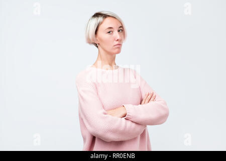 Sûr de graves hipster girl in pink sweater posant avec les mains croisées Banque D'Images