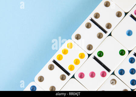 Passage libre de dominos blancs avec des points colorés sur un fond bleu avec copie espace Banque D'Images