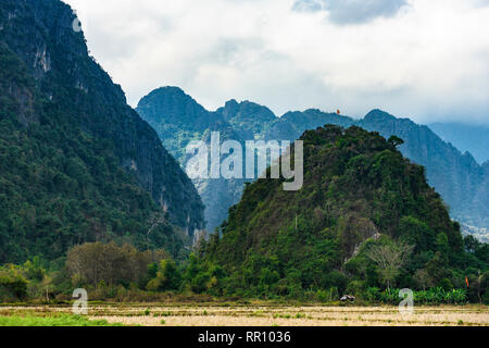 Vue magnifique d'une des montagnes de calcaire éclairée par quelques rayons de soleil qui filtre à travers quelques nuages. Vang Vieng, Laos. Banque D'Images