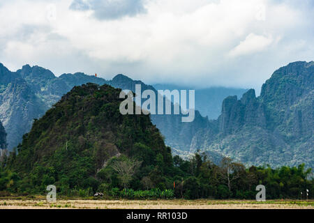 Vue magnifique d'une des montagnes de calcaire éclairée par quelques rayons de soleil qui filtre à travers quelques nuages. Vang Vieng, Laos. Banque D'Images