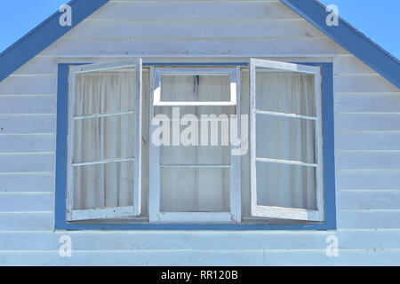 Façade toiture de maison traditionnelle en bois peint en blanc et bleu avec bardage horizontal et volet multi fenêtre. Banque D'Images