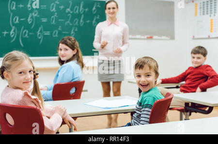 Les élèves de la classe les mains pour répondre à une question Banque D'Images