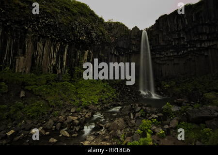 Une longue exposition de cascade Svartifoss avec sa chute d'eau plus de colonnes de basalte avec ciel couvert en haut. Le parc national de Skaftafell dans le sud de l'Icelan Banque D'Images