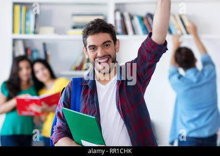 Cheering male student espagnol avec groupe d'étudiants de l'université de la bibliothèque Banque D'Images