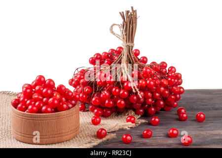 Dans petits fruits rouges mûrs viburnum un bol en bois sur la table isolé sur fond blanc Banque D'Images