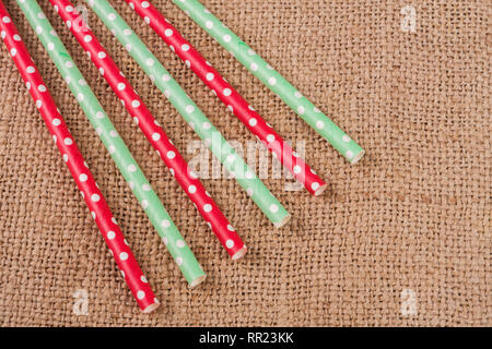 Pailles à rayures potable colorés sur fond de toile de jute Banque D'Images