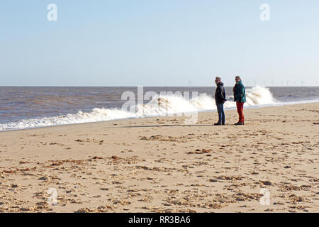 Deux personnes regardant la mer sur une belle journée d'hiver dans la région de East Norfolk à Winterton-sur-Mer, Norfolk, Angleterre, Royaume-Uni, Europe. Banque D'Images