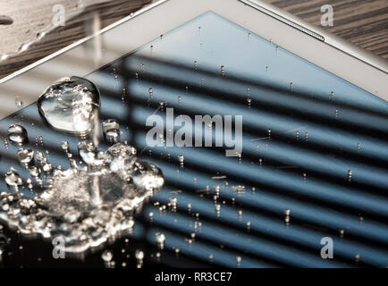 Renversé sur le comprimé d'eau, gouttes d'eau sur l'écran de tablette Banque D'Images