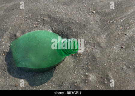 Bouteille de boisson gazeuse en plastique vide laissée incrustée dans le sable argenté de la plage. Pour la pollution de plage en plastique, plastique polluant de l'océan, bouteilles en plastique Royaume-Uni plage. Banque D'Images