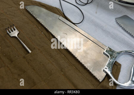 Vintage scie de chirurgie et d'une fourchette le poser sur une table. Dix-neuf siècles d'instruments de chirurgie militaires sont prêts à traiter les soldats blessés au cours d'une bataille Banque D'Images