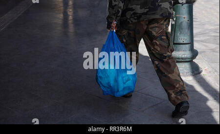 L'utilisation des sacs en plastique. L'homme en uniforme militaire hoding un sac en plastique bleu. Vue rapprochée, copy space Banque D'Images