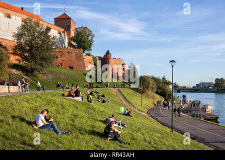 Les gens se détendre sur l'herbe en dessous du château de Wawel à Vistule dans la ville de Cracovie, Pologne Banque D'Images