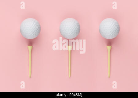 Balle de golf et trois tee en bois sur fond rose closeup
