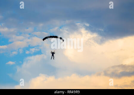 Parachutiste tombant du ciel en soirée coucher du soleil Ciel dramatique. Le sport de loisirs, Paratrooper silhouette sur le ciel de couleur. Banque D'Images