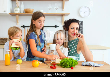 Happy young brunette mère avec mignon enfants le petit-déjeuner à l'accueil Banque D'Images