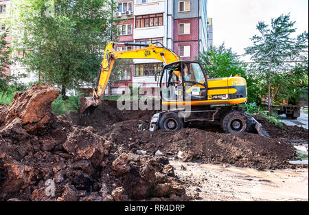 Samara, Russie - 25 mai 2017 : excavatrice jaune de creuser une tranchée près de l'immeuble en été journée ensoleillée Banque D'Images