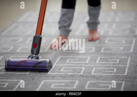 Garçon en utilisant un aspirateur lors du nettoyage de tapis dans la chambre Banque D'Images