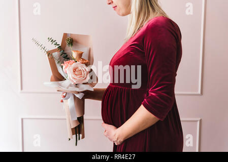 Pragnant femme tenant un bouquet de fleurs Banque D'Images