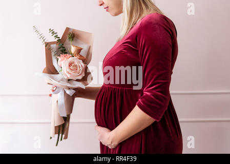 Pragnant femme tenant un bouquet de fleurs Banque D'Images