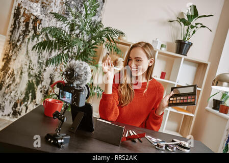 Si facile d'être parfait ! Gai et jeune blogueur présentant une palette de maquillage sur l'appareil-photo pendant l'enregistrement nouveau tutoriel vidéo sur les médias sociaux. Tutoriel Banque D'Images
