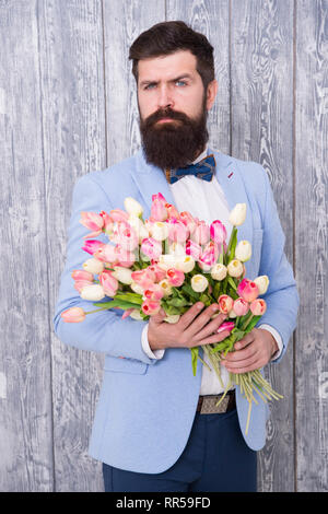 Homme très soigné porter Bow-tie tuxedo tenir fleurs bouquet. Inviter ses sorties. Homme romantique avec des fleurs. Cadeau romantique. Macho prêt date romantique. En attente de Darling. Tulipes pour ma chérie. Banque D'Images