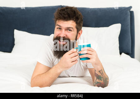 Homme heureux profiter de café du matin. Du café frais. Heureux matin. Homme barbu boire le café du matin. heureux homme barbu au lit. Bon matin commence à partir de café. Jour de départ avec de bonnes nouvelles. Détente à la maison. Banque D'Images