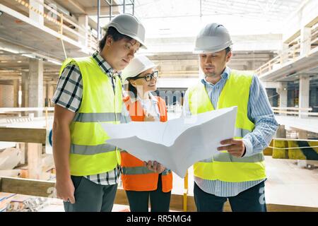 Groupe d'ingénieurs, constructeurs, architectes sur le site de construction, à la recherche dans le plan stratégique. La construction, le développement, le travail d'équipe et les personnes concept. Banque D'Images