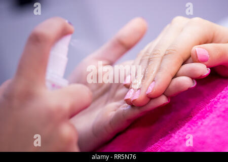 Women's hands on pink towel in nail salon. Banque D'Images