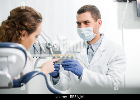 Le choix de palette de couleurs femme dents près de dentiste en masque et des gants en latex Banque D'Images