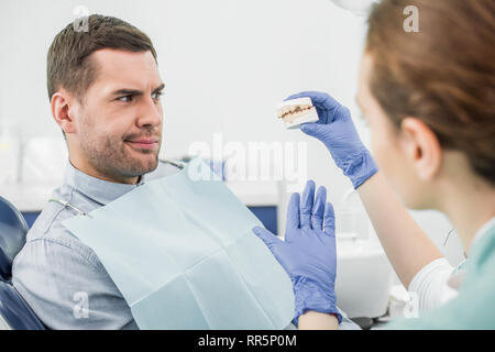 Focus sélectif de la confondre man modèle dents dans la main de femme dentiste Banque D'Images