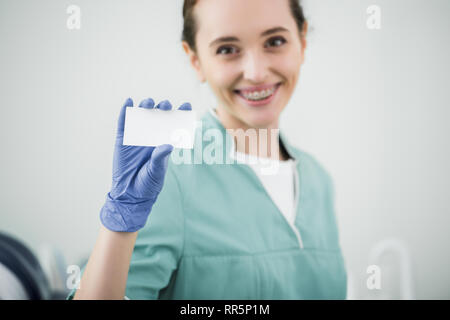 Focus sélectif de carte vierge dans la main de femme joyeuse dentiste Banque D'Images