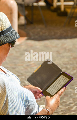GARDONE RIVIERA, ITALIE - Septembre 2018 : la lecture d'un roman sur un e-reader. Banque D'Images