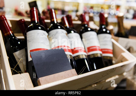 Plusieurs bouteilles de vin avec des étiquettes vides dans des caisses en bois sur fond flou. Banque D'Images