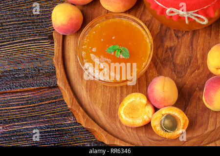 Confiture d'abricot dans un bocal en verre sur une vieille table en bois brun, vue de dessus (selective focus). Banque D'Images