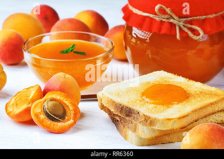 Confiture d'abricot dans un bocal en verre sur une vieille table en bois blanc(selective focus). Banque D'Images