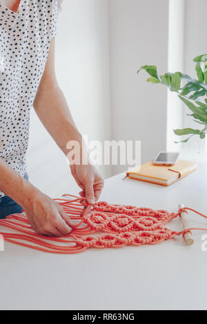 Close up of female hands weaving macrame dans un atelier d'accueil. Banque D'Images