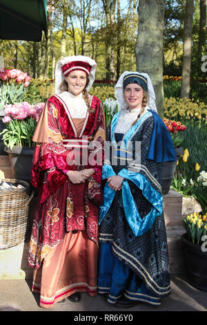 Deux belles jeunes filles en costume traditionnel accueil souriant au printemps en jardin de fleurs Keukenhof. De nombreuses tulipes colorées Banque D'Images