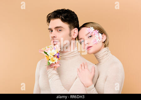 Bel homme debout avec une belle petite amie et montrant hush signe isolé sur beige Banque D'Images