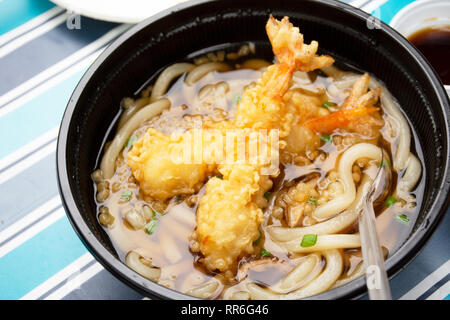 Les nouilles Udon ou soupe de nouilles de style japonais, avec la garniture de crevettes tempura croustillante sur table en plein air au jardin du Japon village de Ayutthaya, Thaïlande Banque D'Images