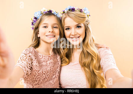 Focus sélectif de belle mère et fille adorable et souriant à la caméra à sur fond jaune Banque D'Images