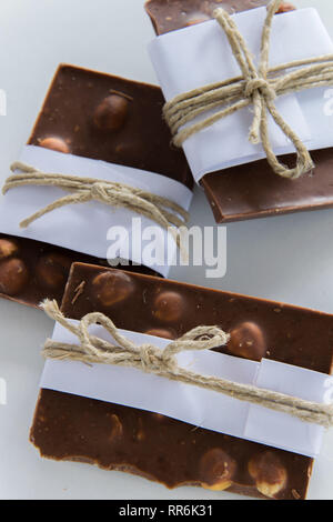 Vue de dessus de morceaux de chocolat enveloppé dans du papier blanc et ficelle rustique sur le fond blanc Banque D'Images