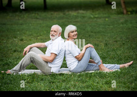 Happy senior couple reposant sur un tapis de yoga sur pelouse verte dans la région de park Banque D'Images