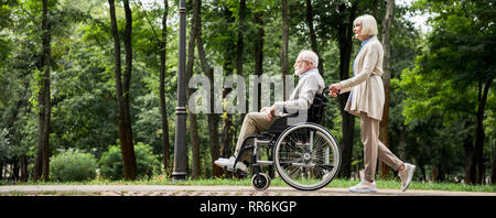 Senior woman avec son mari en fauteuil roulant : walking in park Banque D'Images