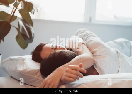 Couple tout en dormant dans le lit avec la lumière du soleil Banque D'Images